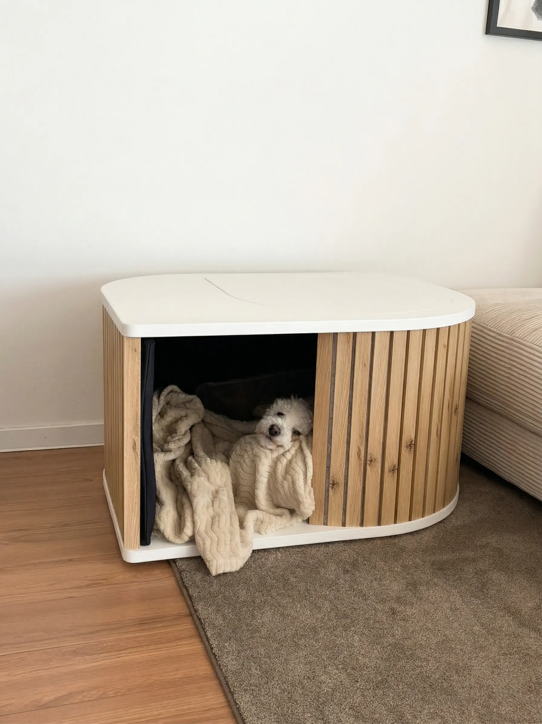 Swoof wooden dog retreat in solid walnut — warm dark wood slats with a sculpted entrance, photographed in a calm living room setting